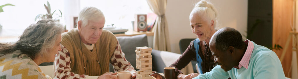 Senior friends having fun playing game of Jenga together in an assisted living facility