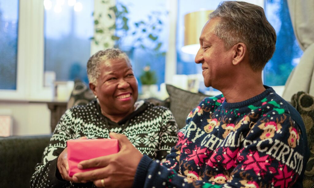 Senior couple sitting on the sofa holding Christmas gifts